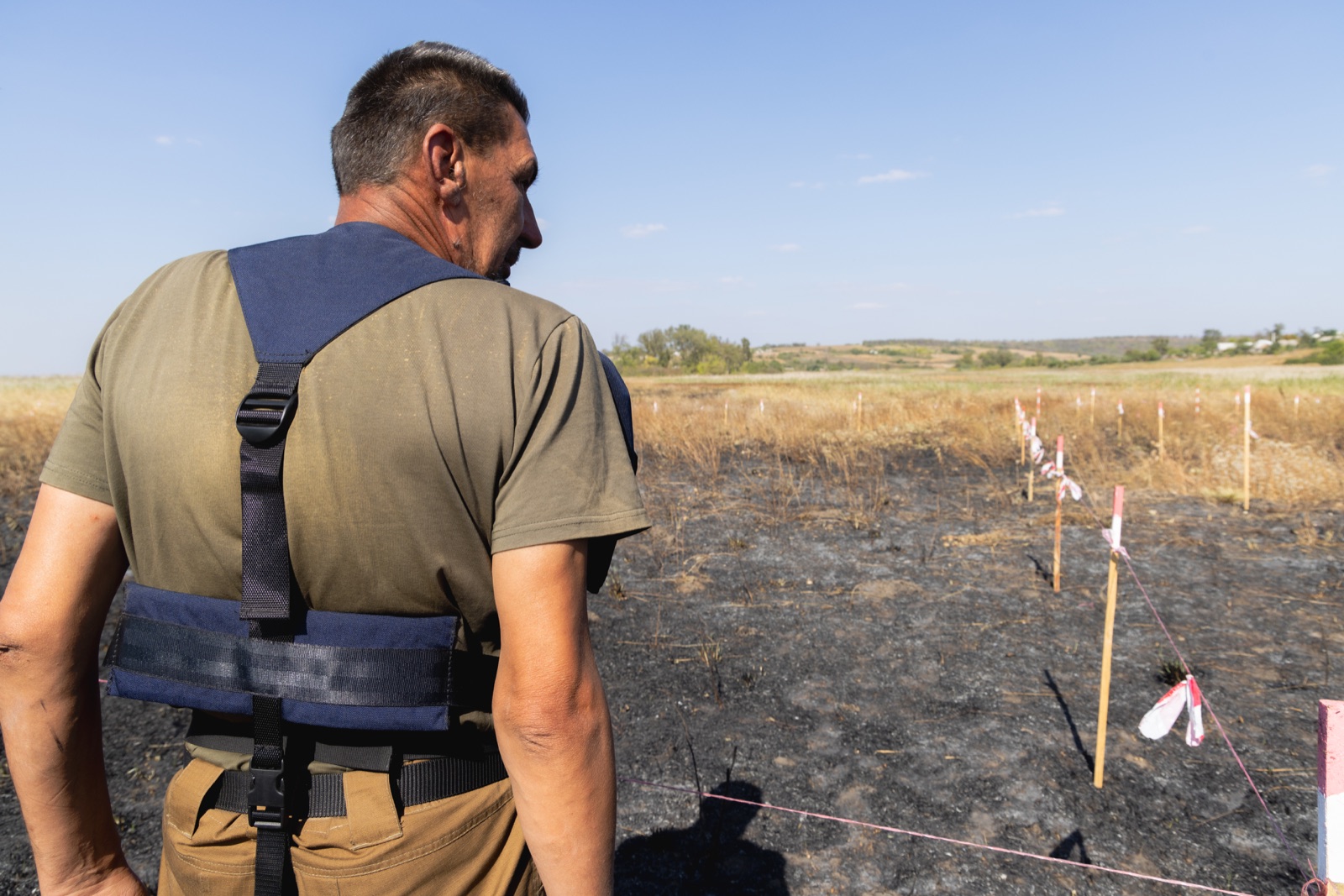 A deminer standing beside a marked clearance lane