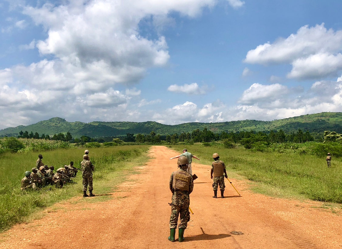 Military personnel conducting a practical explosive-threat search exercise on a rural road in East Africa